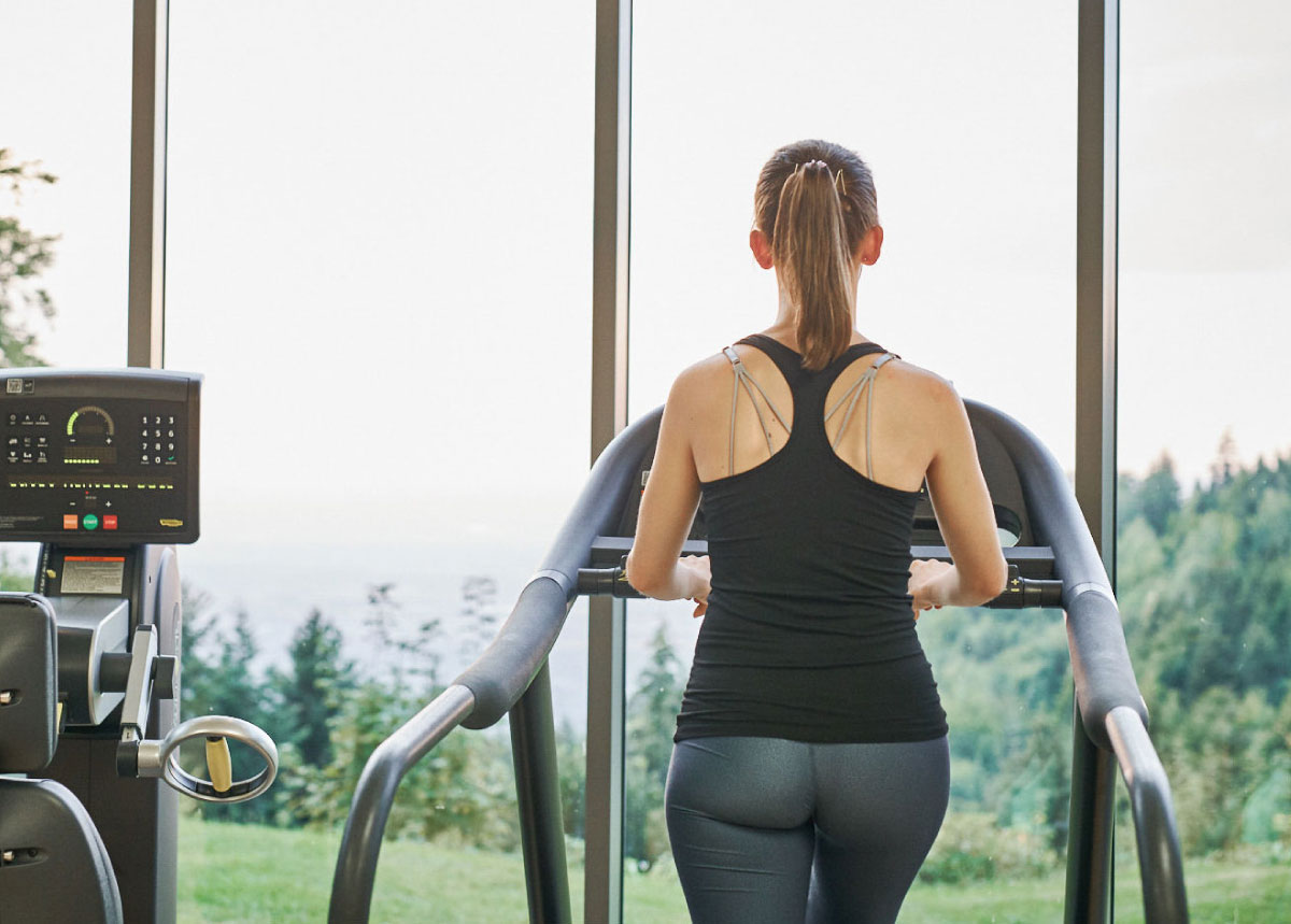 Frau trainiert auf Laufband, Rückansicht