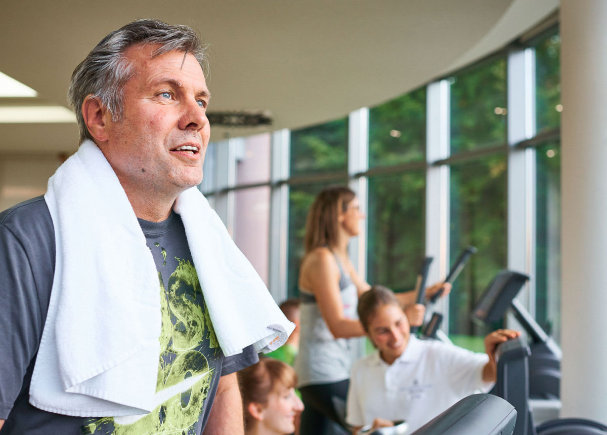 Mann beim Sporttrainung, zwei Frauen im Hintergrund