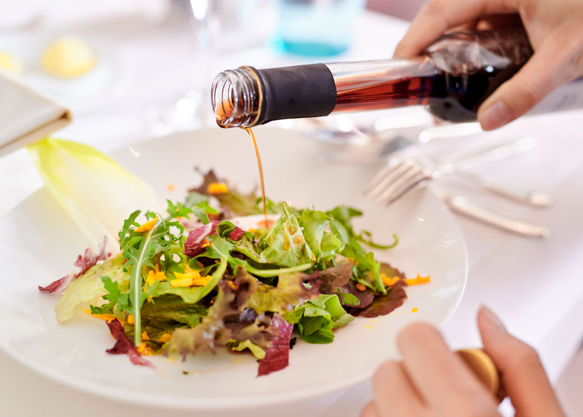 Teller mit buntem Salat und Flasche mit Essig